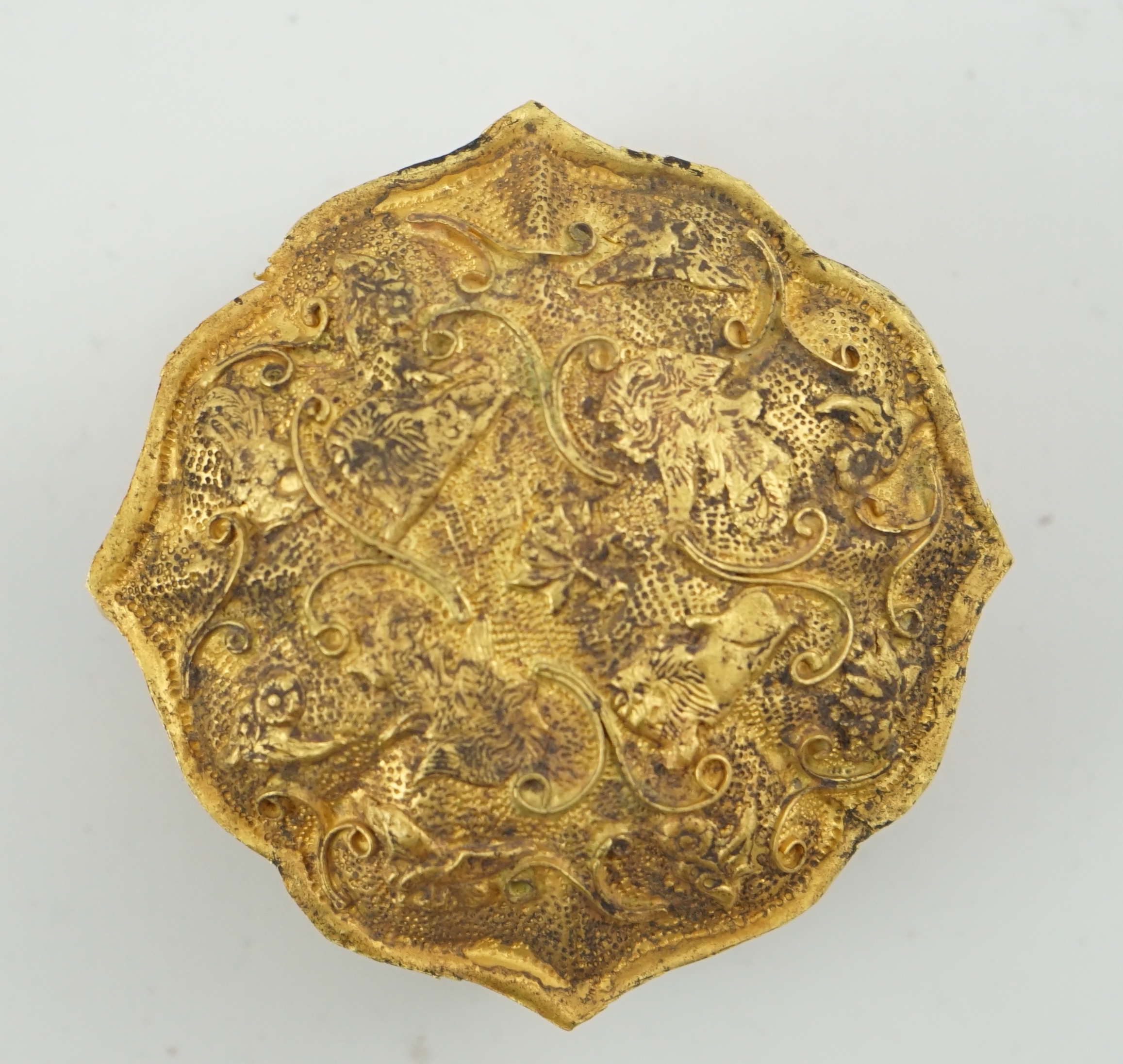 'An 18th century Chinese gilt repousee box & cover, probable Liao Dynasty', of petal lobed form, decorated with lions amid filigree scroll work, 5.5cm across